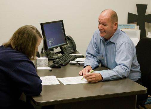 professor talks to student sitting at desk